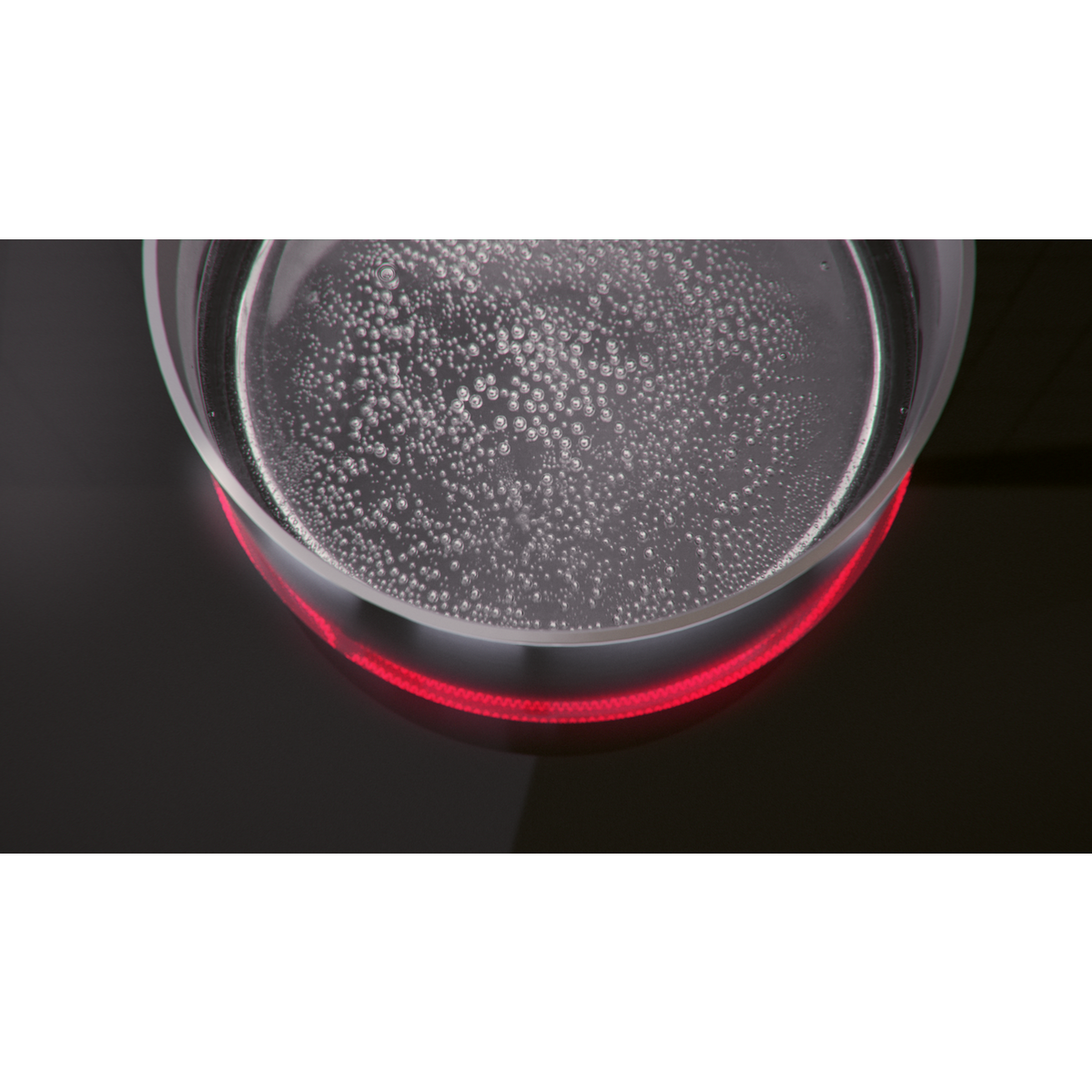 Agua hirviendo en una olla de vidrio sobre una estufa negra, iluminada en rojo.