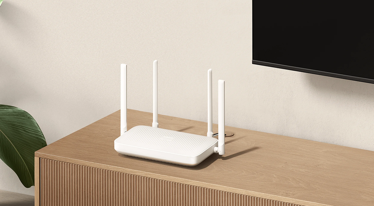Fehér router 4 antennával egy faasztalon, tévé a háttérben.