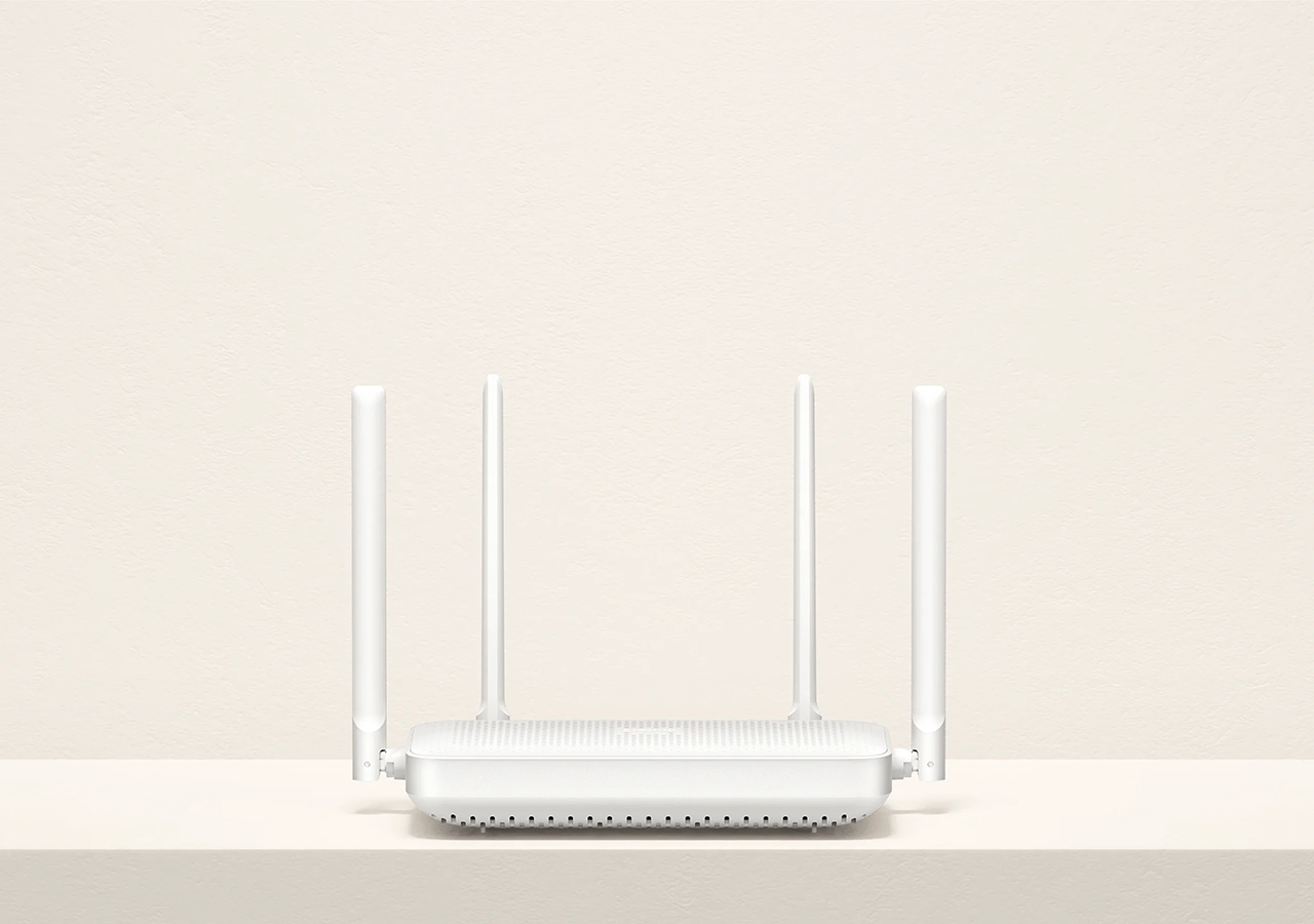 Fehér router négy antennával bézs háttér előtt, polcon elhelyezve.