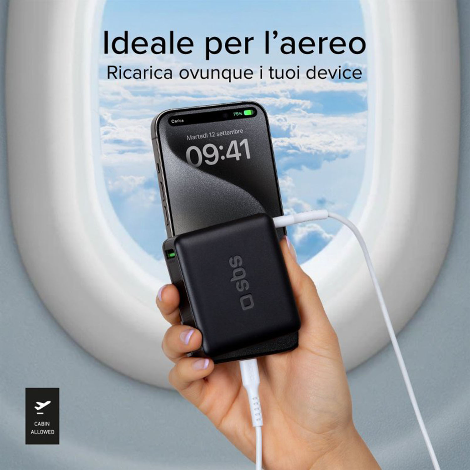 Mano che tiene un caricatore nero con un telefono, finestrino dell'aereo sullo sfondo.