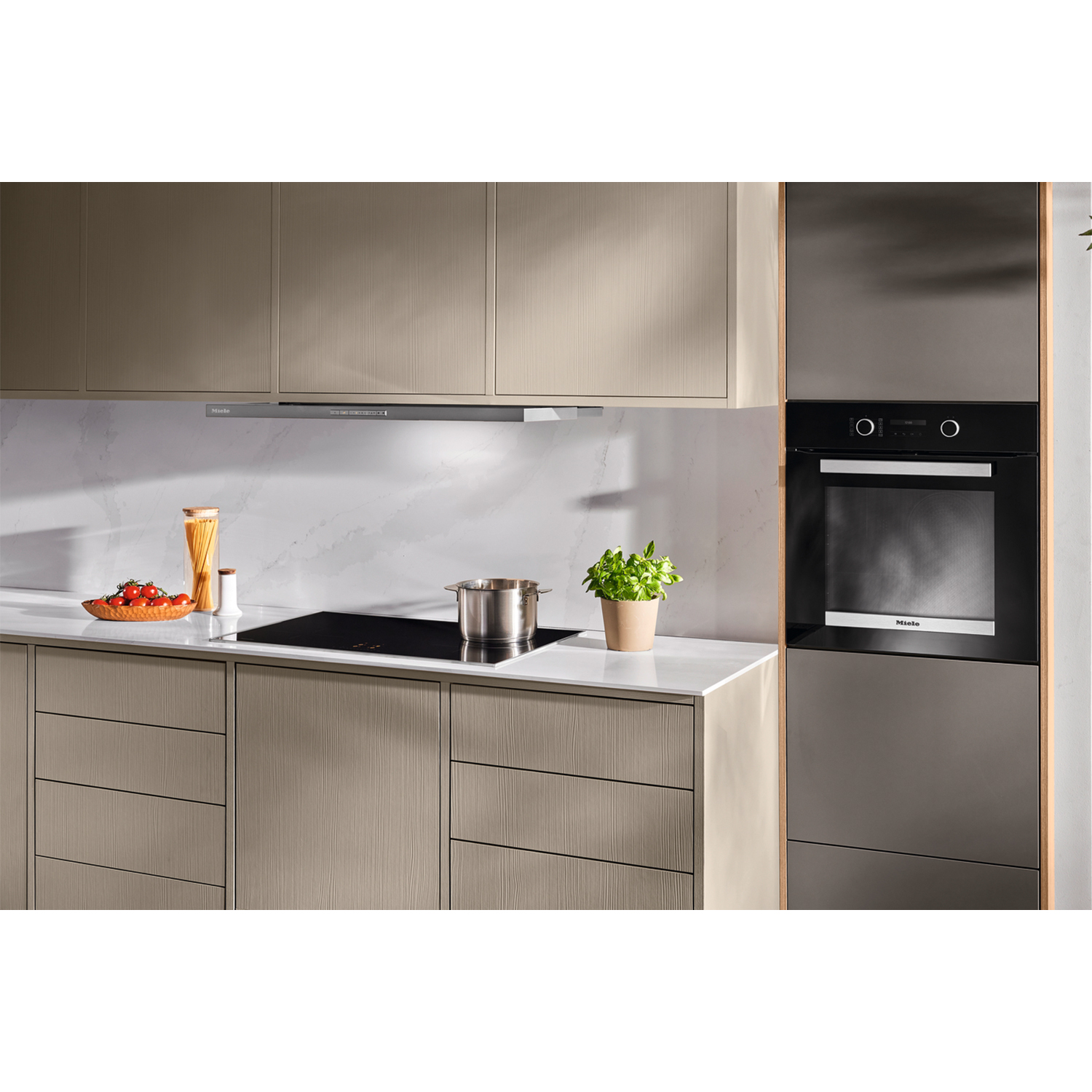 Una cucina moderna con mobili in legno chiaro, piani di lavoro bianchi e un forno a incasso.