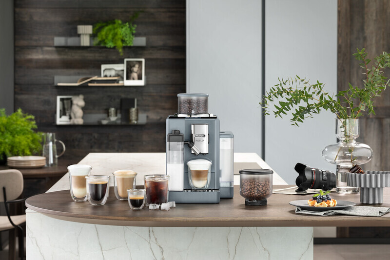 A coffee machine with various coffee cups and a plate of waffles on a wooden countertop.