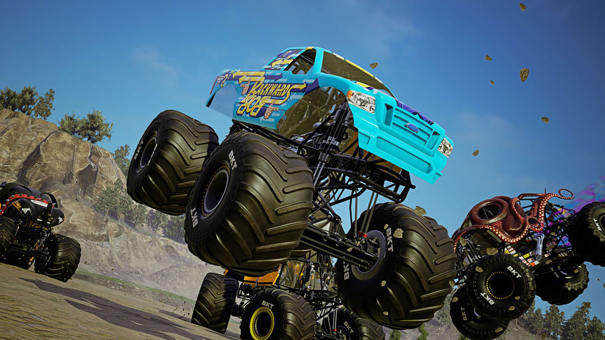 Monster truck in volo. Camion blu a fuoco, altri sullo sfondo. Terra e cielo nella scena.