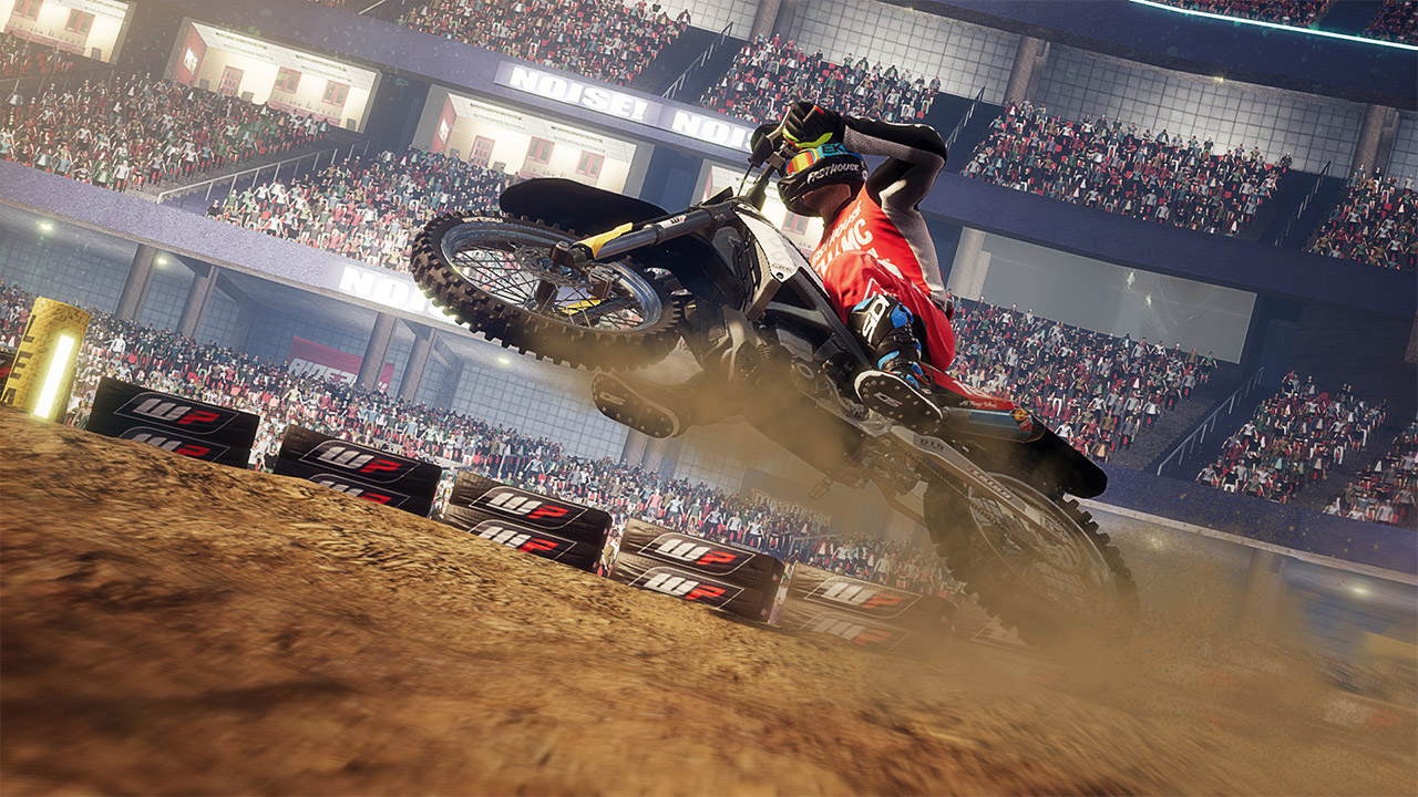 Pilota di motocross in volo, in gara in uno stadio su pista sterrata.