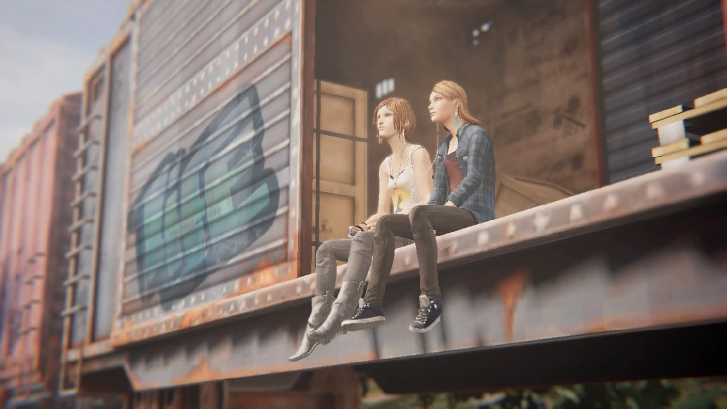 Deux jeunes femmes sont assises sur un wagon. Elles regardent ailleurs, la scène est un peu rustique.