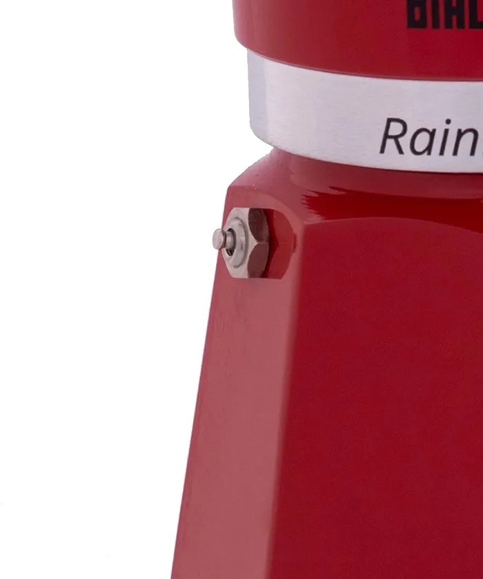 Közelkép egy piros kávéfőzőről. Ezüstszalaggal rendelkezik, rajta a "Rain" szóval és egy kis gombbal.