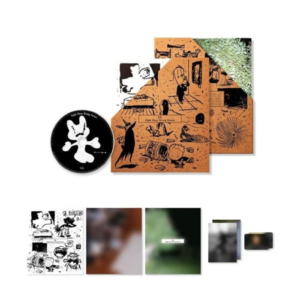 Verschiedene Albumcover, eine CD und eine weiße Cartoonfigur, alles auf einem Stapel.
