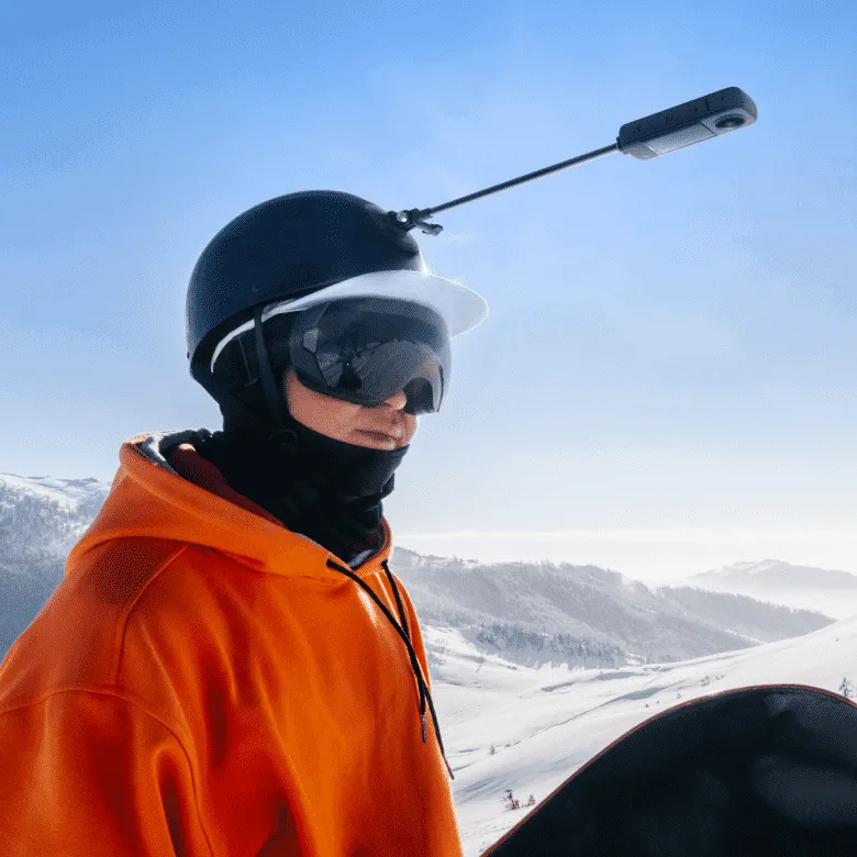 Ein Skifahrer mit Helm und Kamera in verschneiter Berglandschaft.