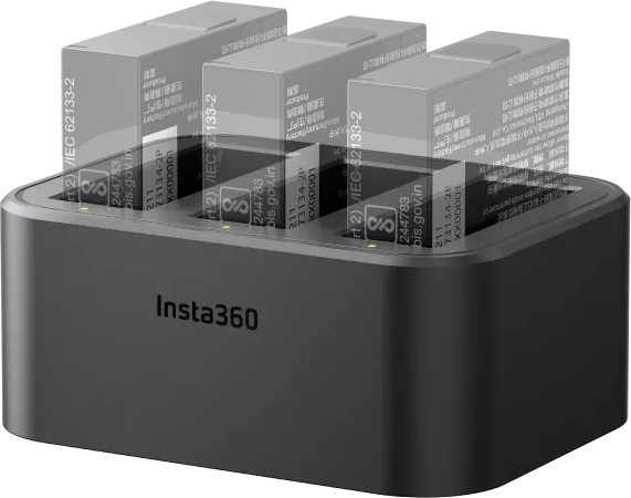 Schwarzes Insta360-Ladegerät mit drei Akkus. Das Ladegerät ist eingesteckt, grüne Lichter zeigen das Laden an.