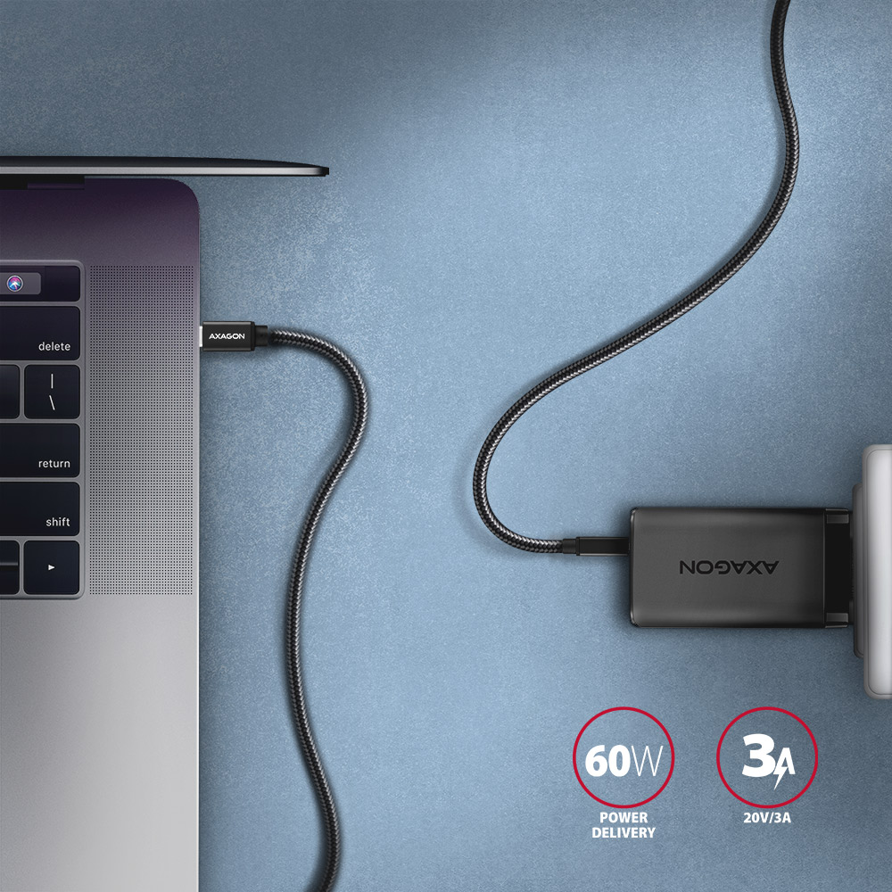Laptop töltése Axagon töltővel. Fekete kábel csatlakozik a laptophoz, a hálózati adapterhez és a fali aljzathoz. 60W Power Delivery.