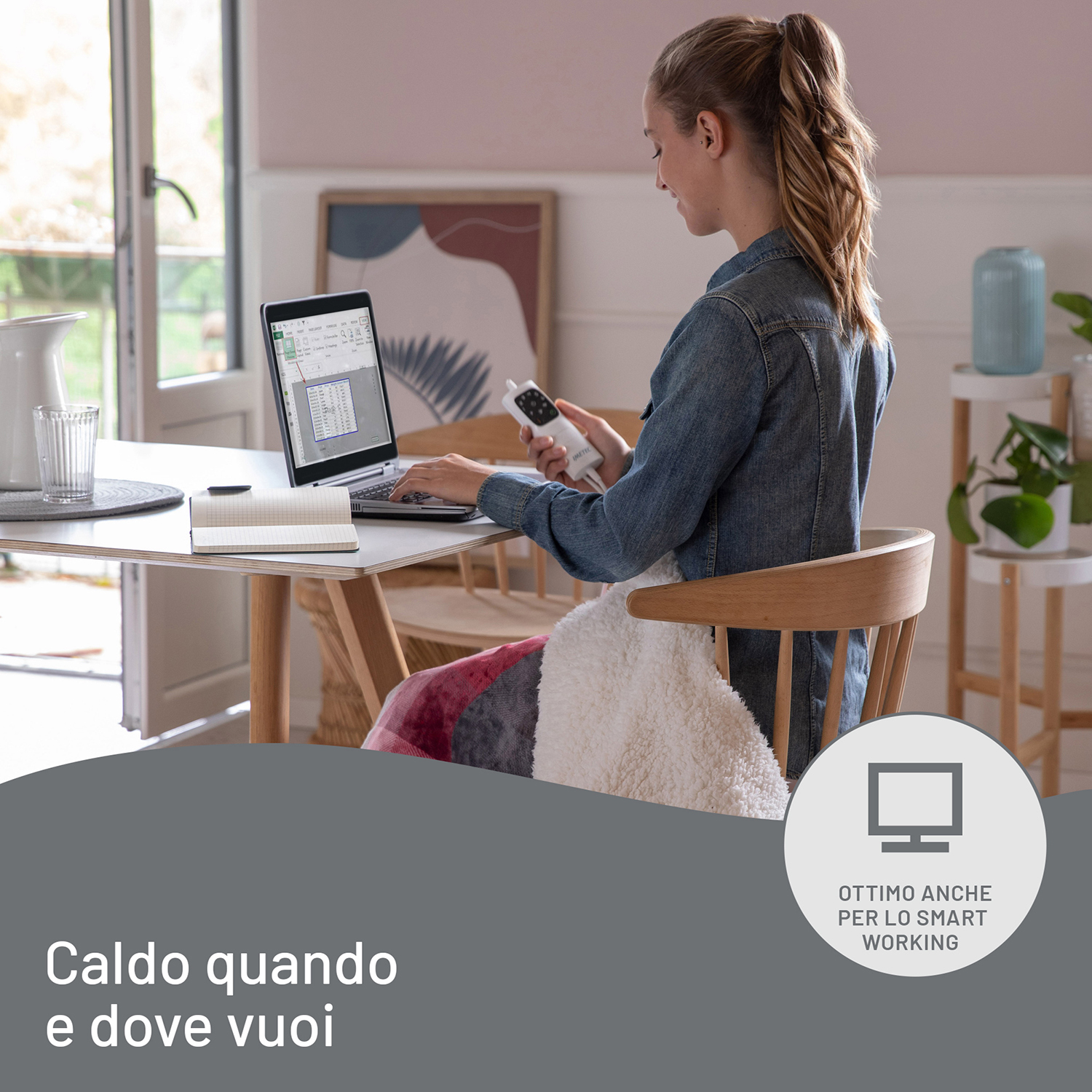 Una donna lavora su un laptop a un tavolo, con un baby monitor e testo nella parte inferiore dell'immagine.