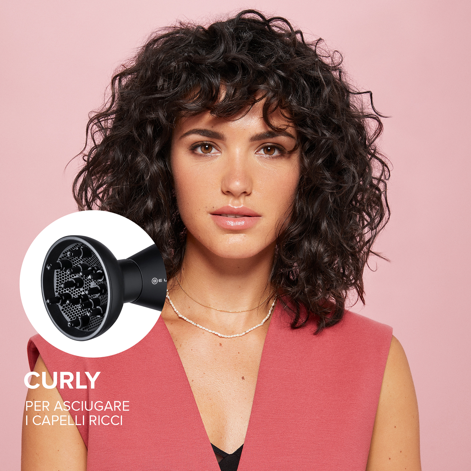 Donna con capelli ricci, che asciuga con un diffusore. Sfondo rosa, asciugacapelli nero e testo.