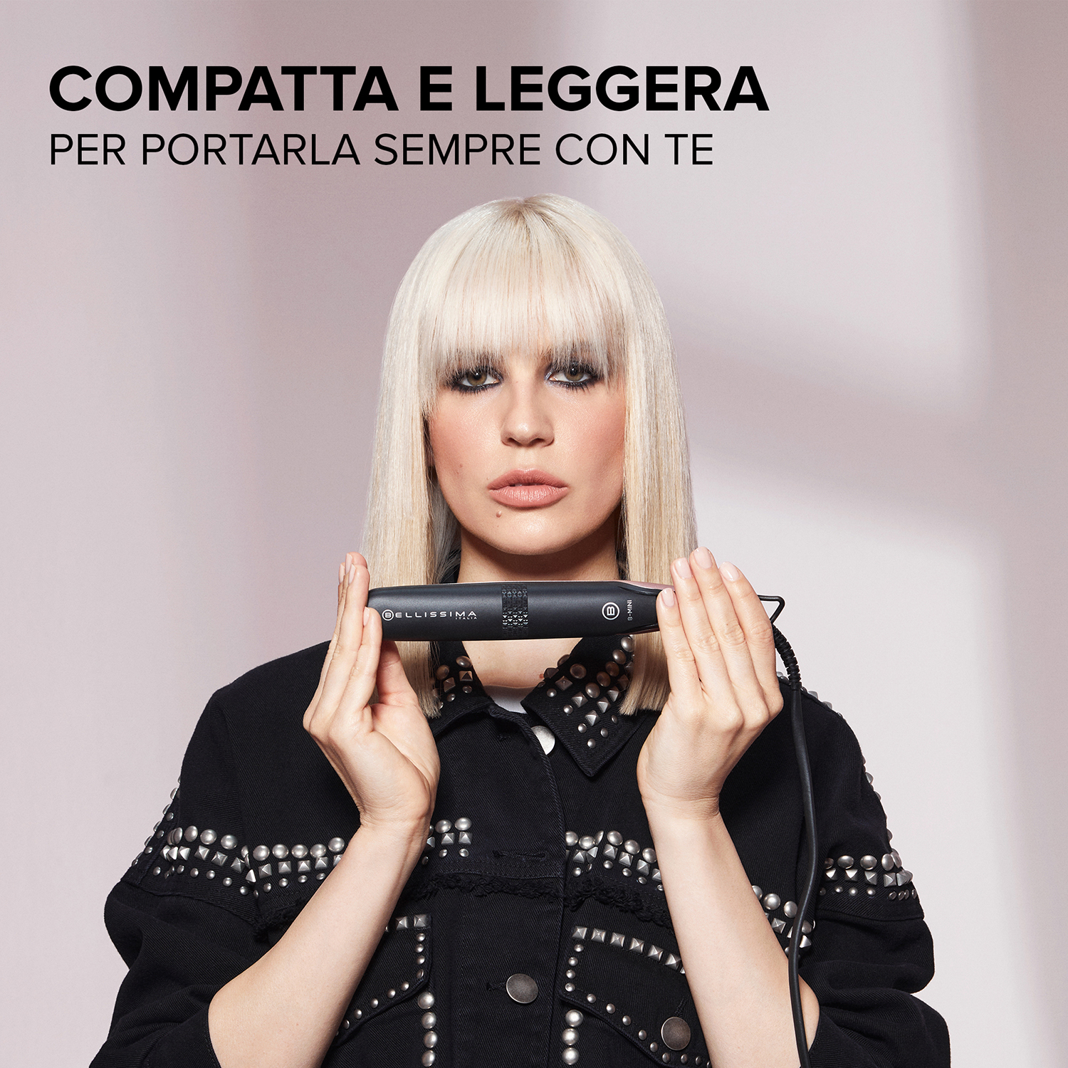 Donna bionda che tiene un regolacapelli nero. Il testo dice compatto e leggero da portare con te.