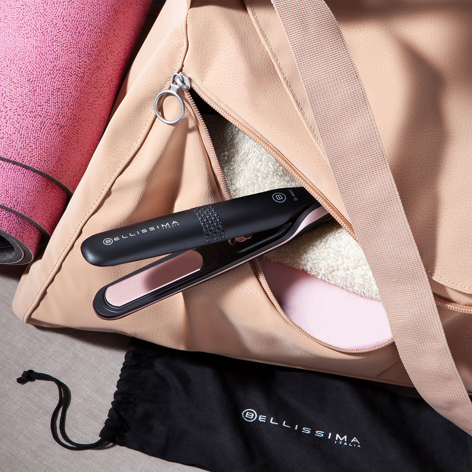 Piastra per capelli nera e rosa in una borsa da palestra pesca, tappetino yoga.