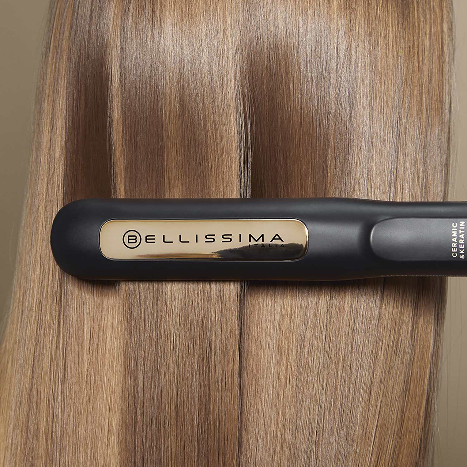 Capelli acconciati con una piastra nera e oro. Sfondo beige.