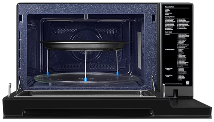 Wnętrze kuchenki mikrofalowej ze szklaną tacą i metalowym stojakiem. Otwarte drzwi i czarne wnętrze.