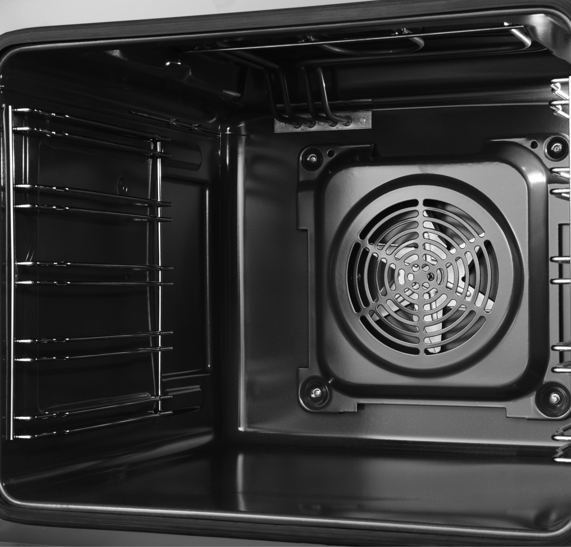 Wnętrze piekarnika. Wnętrze jest czarne, z rusztami i widocznym wentylatorem.