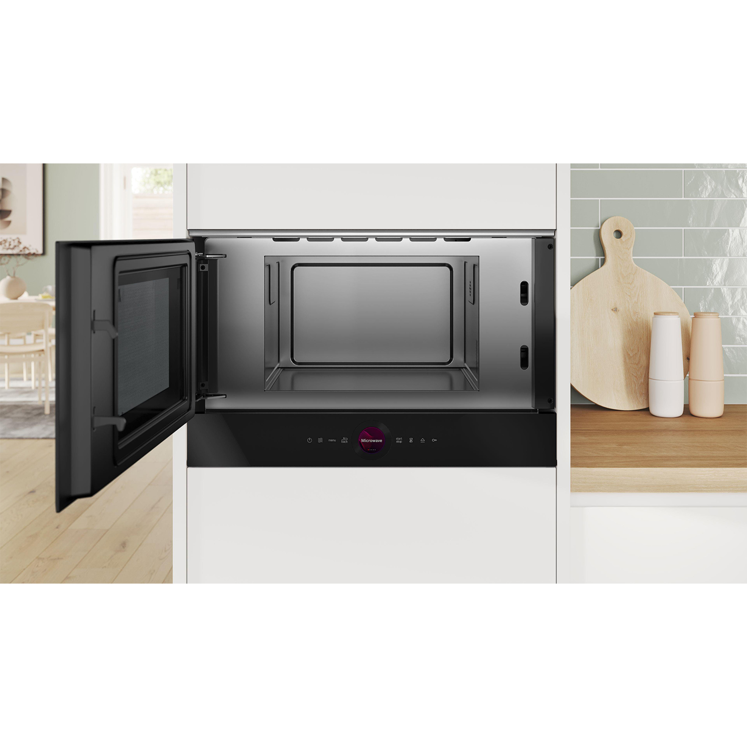 Un forno a microonde integrato con la porta aperta. Legno chiaro e un tagliere sono accanto.