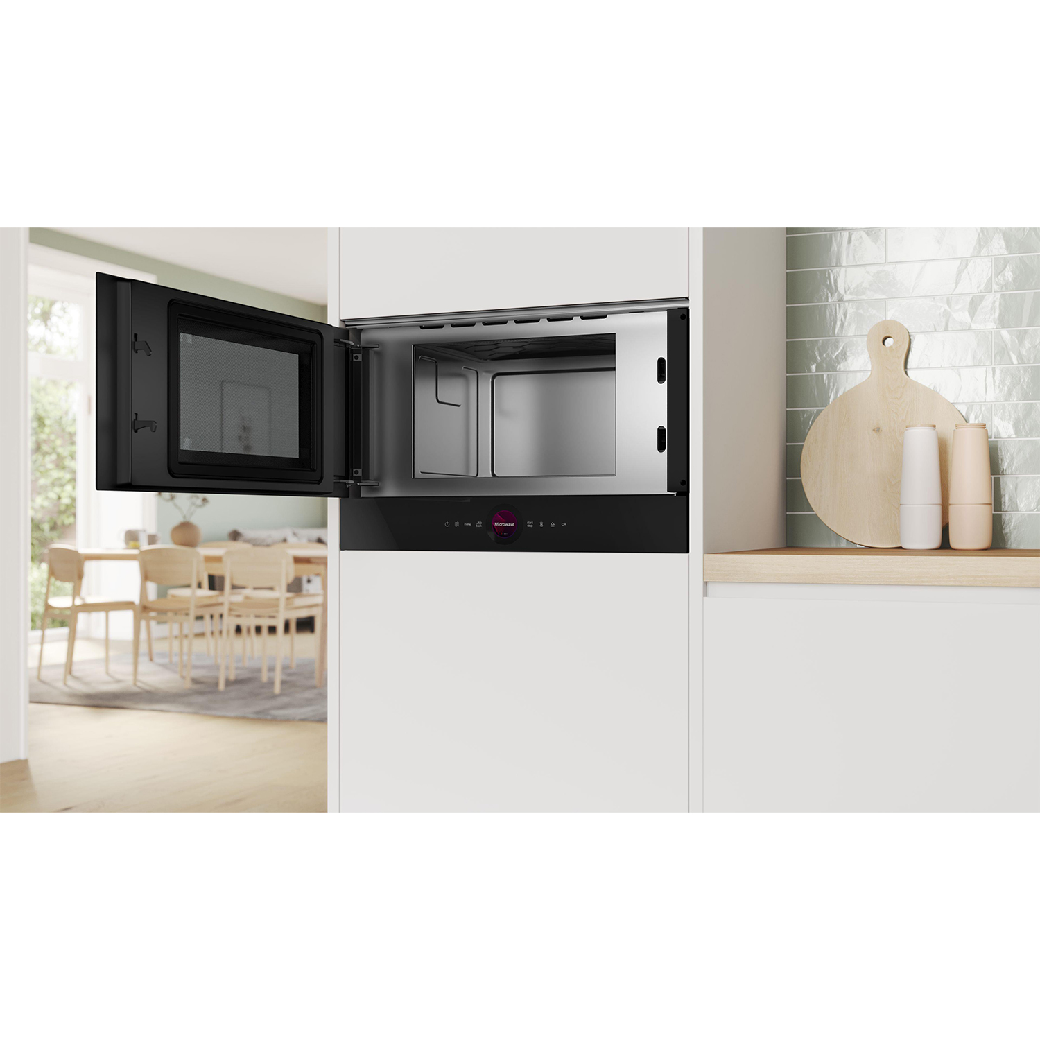 Forno a microonde integrato. Porta nera aperta, interno visibile. Cucina bianca, piano di lavoro in legno, parete verde chiaro.