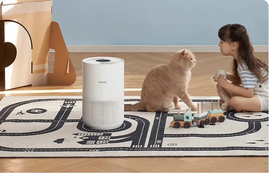 Enfant, chat et purificateur d'air sur un tapis. Jouets à droite.