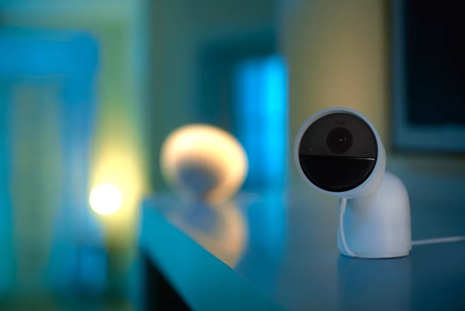 Biała kamera bezpieczeństwa na biurku. Rozmyte źródło światła w tle.