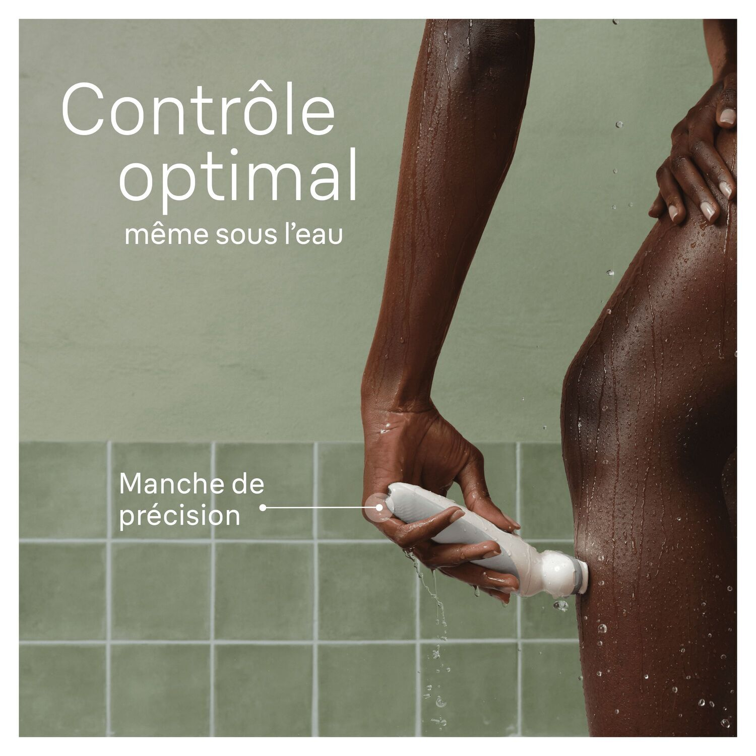 Une femme utilise un appareil sur sa jambe pendant que l'eau coule dessus. Carrelage vert en arrière-plan.