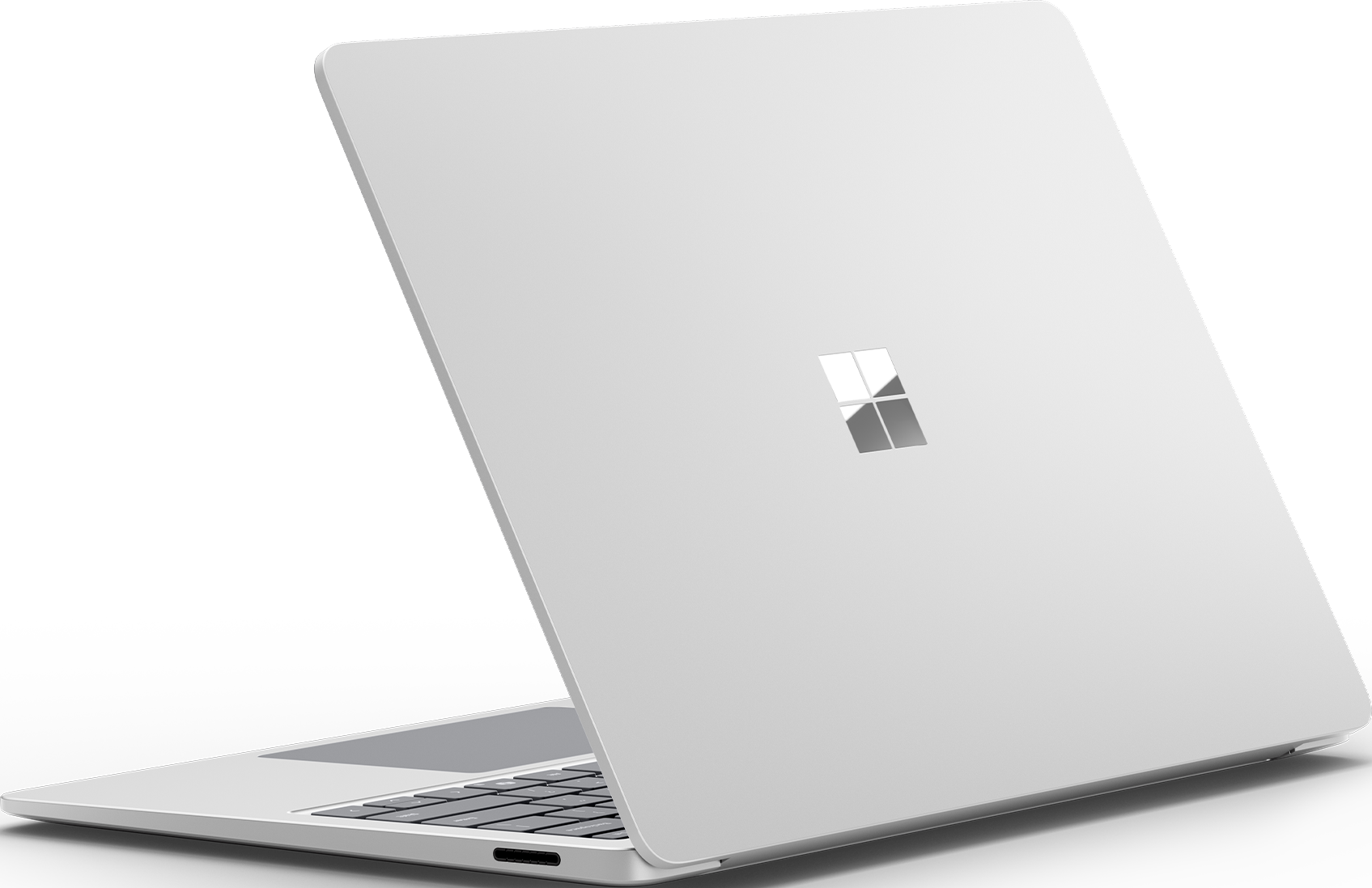 Un laptop grigio chiaro, aperto, con tastiera e logo Microsoft. Sfondo nero.