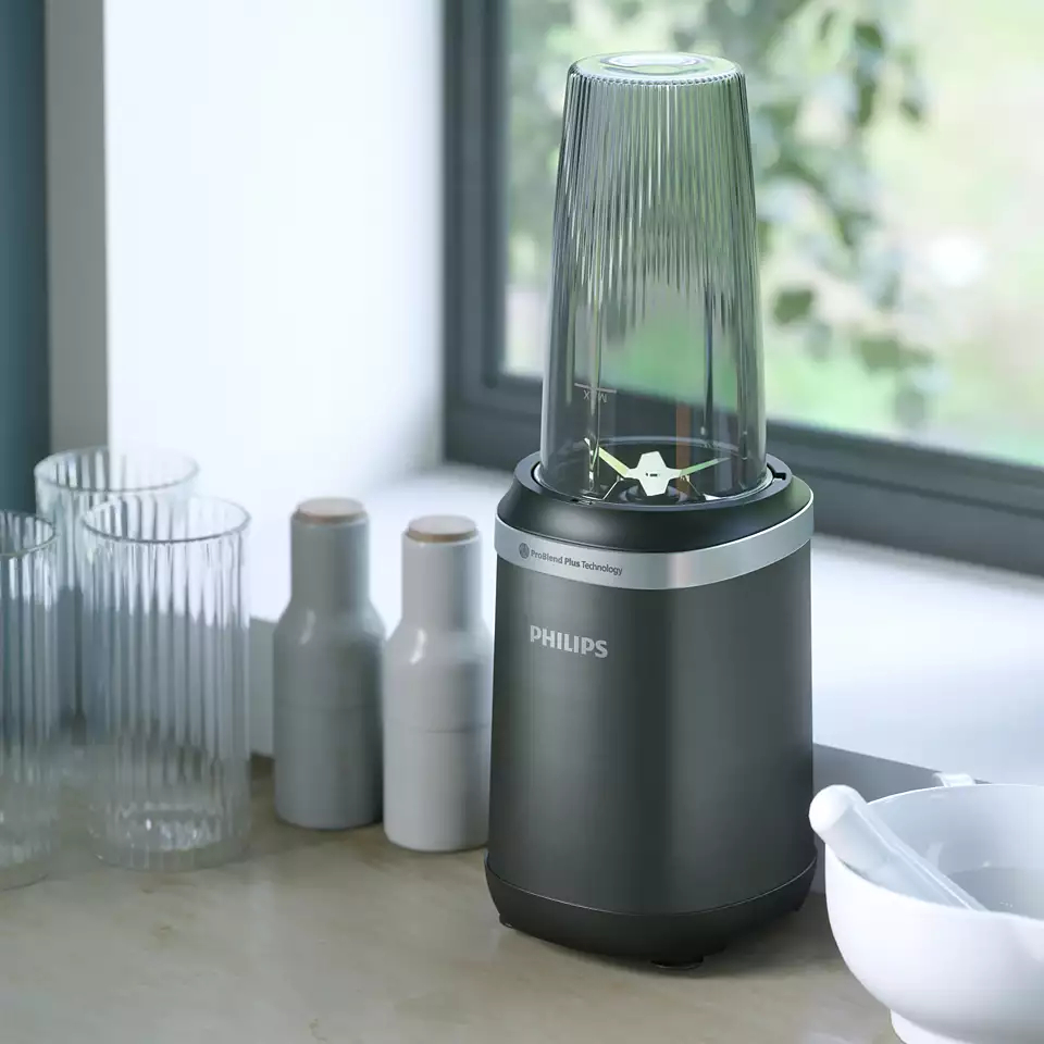 Czarny blender Philips z przezroczystym pojemnikiem. Inne przedmioty są w tle.
