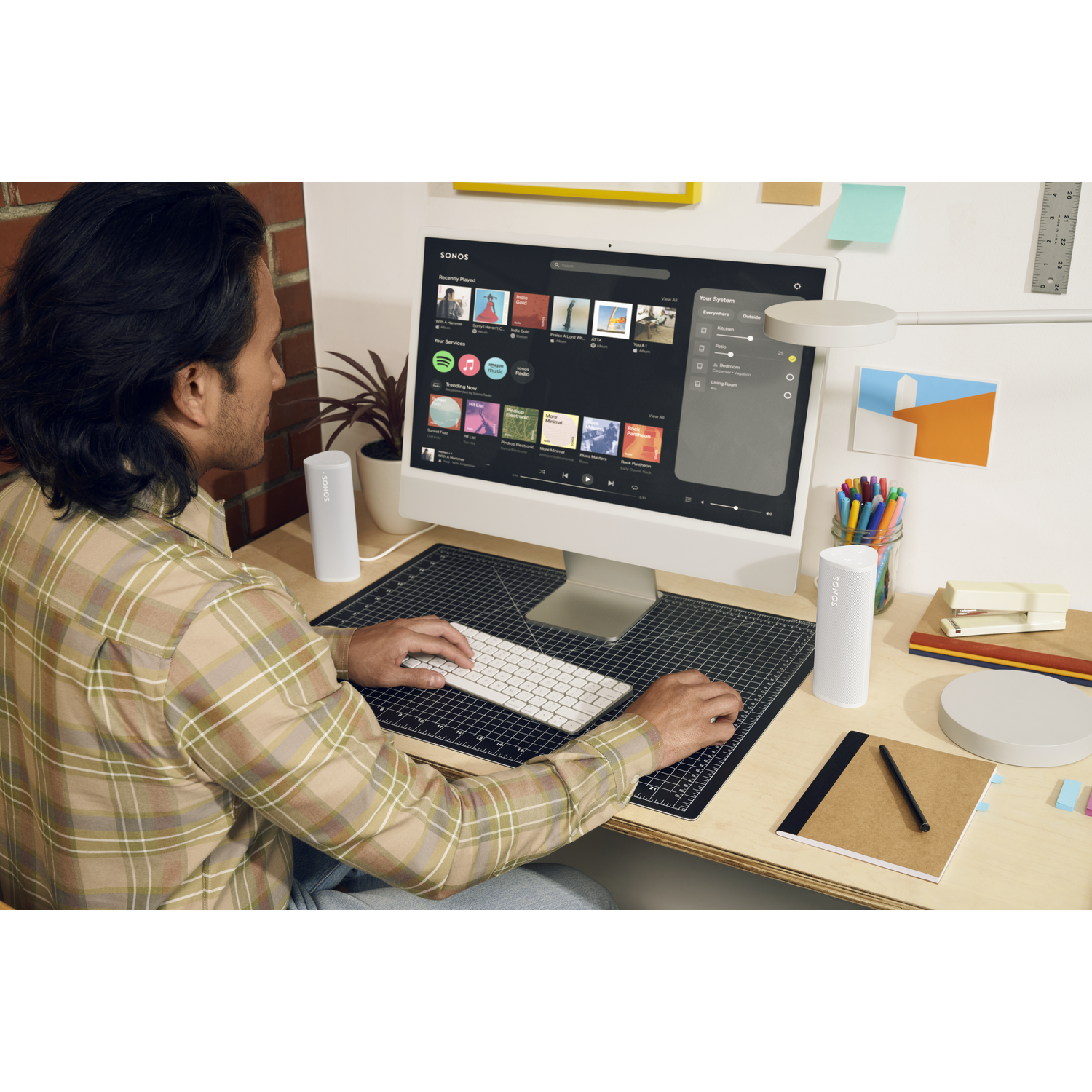 A man using a computer setup with speakers and a monitor displaying an interface. A desk setup.