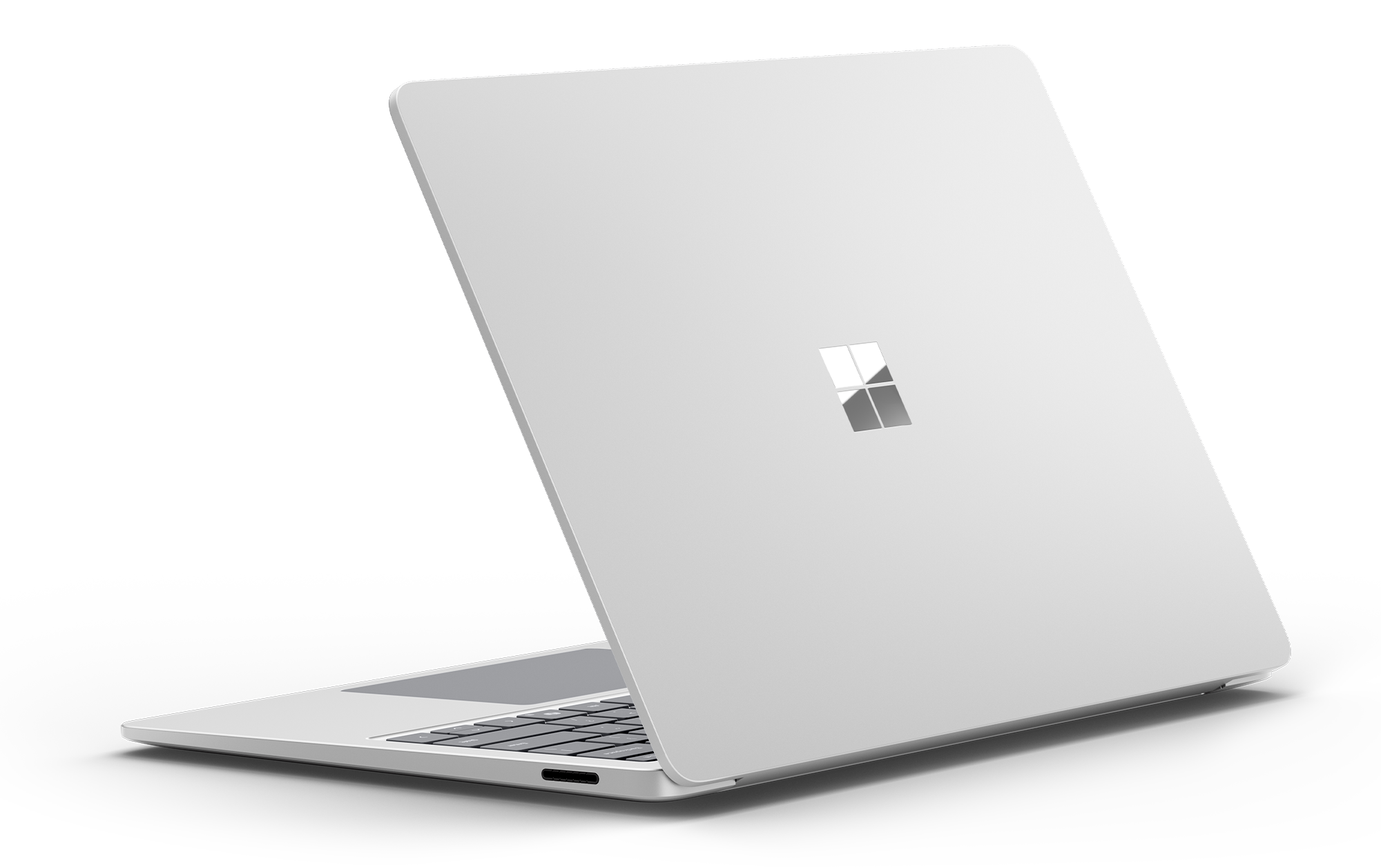 Tył srebrnego laptopa z logo Microsoft. Laptop jest zamknięty, na czarnym tle.