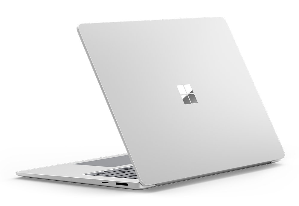 Srebrny laptop jest odchylony do tyłu, pokazując tył z logo Microsoft. Ekran jest otwarty.