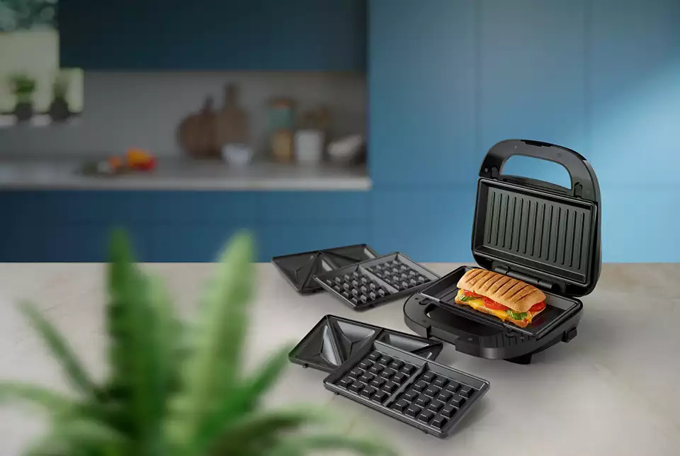 Kanapka jest przygotowywana w opiekaczu. Dodatkowe płyty są na blacie.