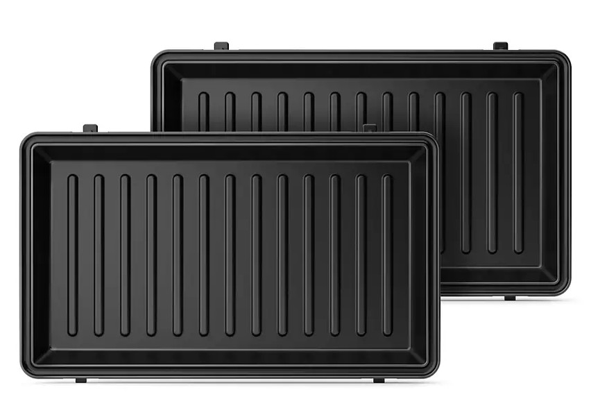 Dwie czarne prostokątne tace z pionowymi liniami, umieszczone obok siebie.