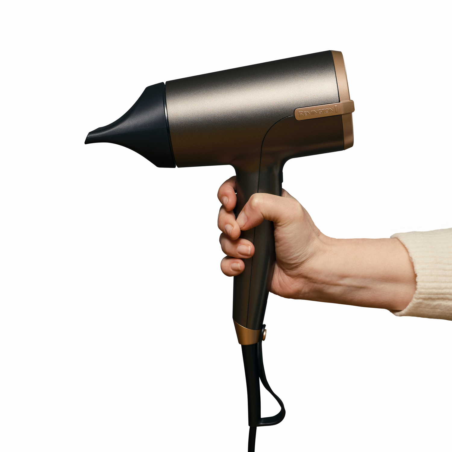 Een persoon houdt een Remington haardroger vast. Het is grijs en brons met een zwart snoer.