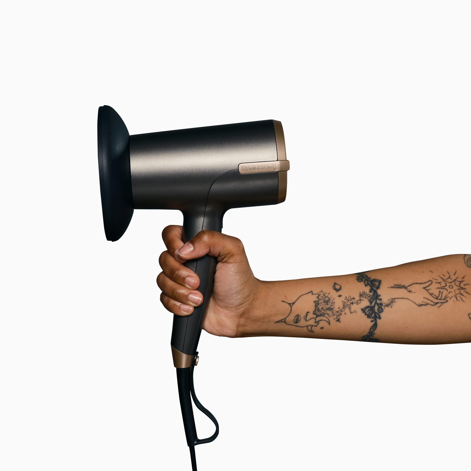 Persoon die een föhn vasthoudt. Arm met tatoeages. Witte achtergrond.