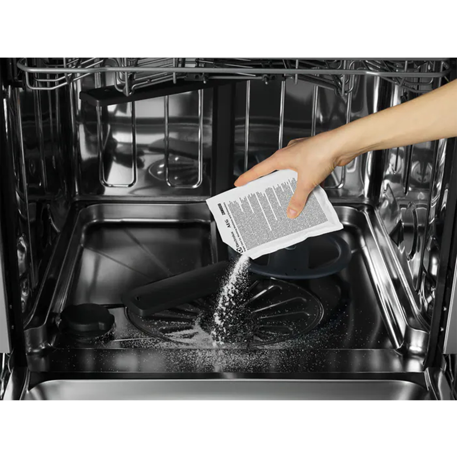 Una mano versa detersivo per lavastoviglie in una lavastoviglie aperta. L'interno è in acciaio inossidabile.