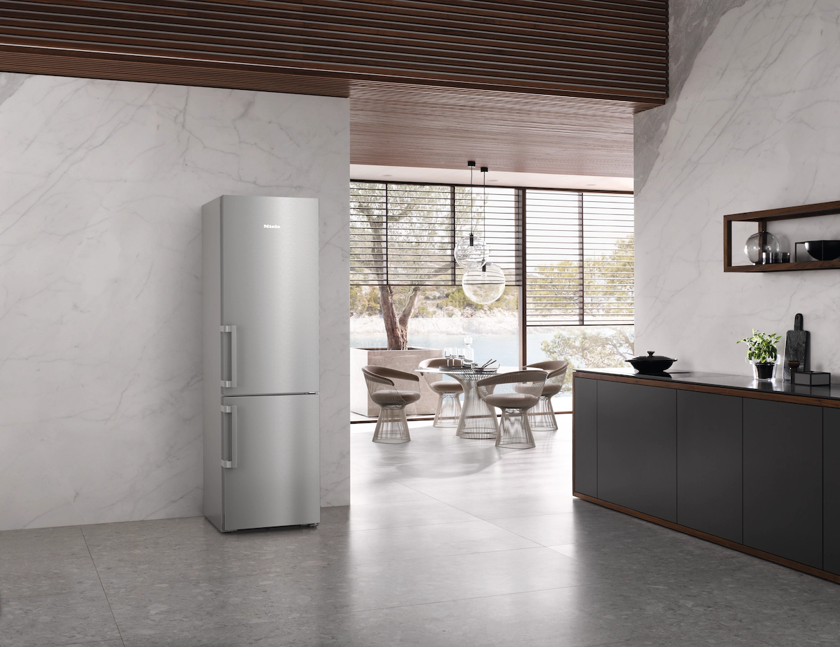 Frigorifero Miele in una cucina moderna, con zona pranzo sullo sfondo.