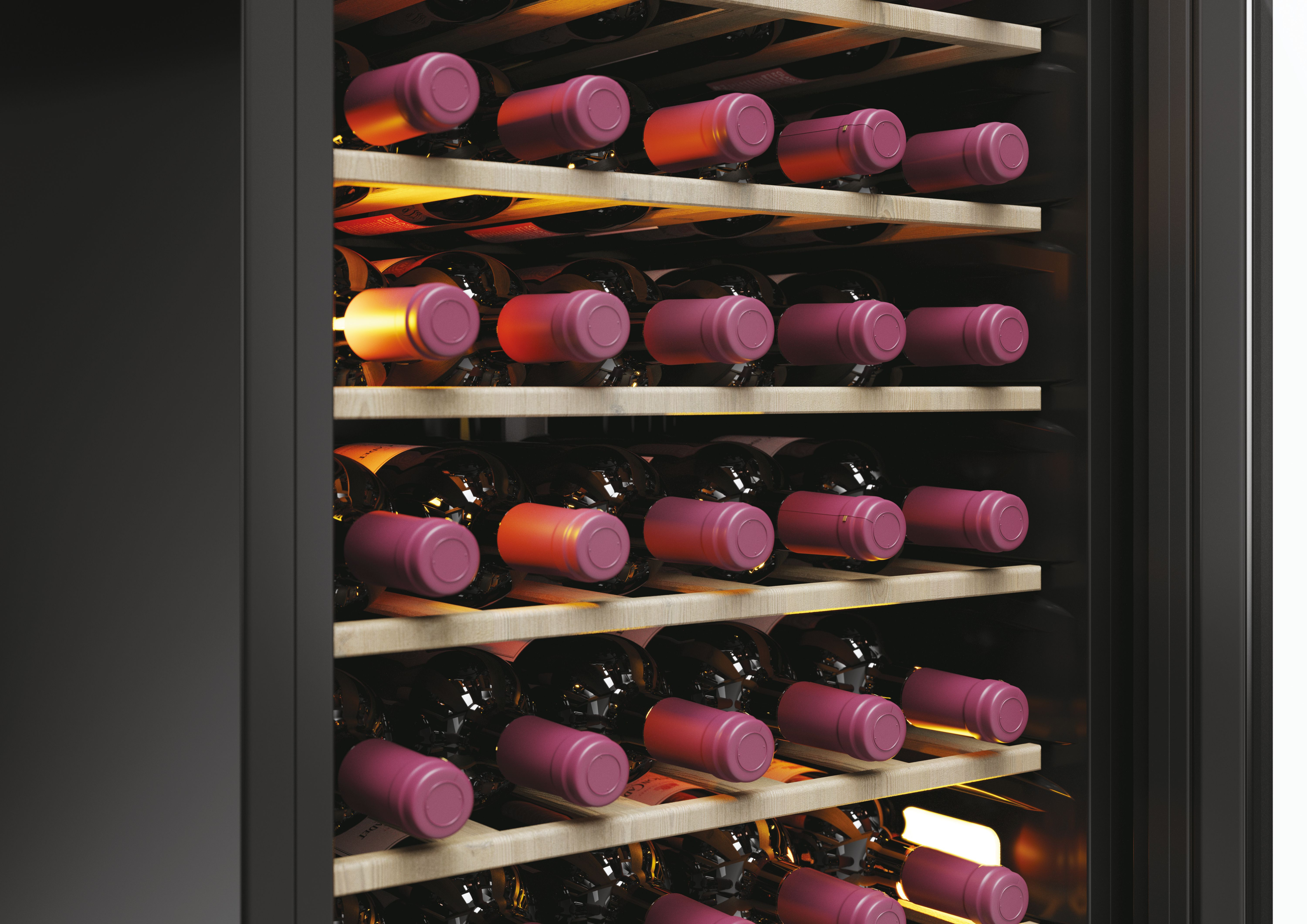 Wein-Kühlschrank-Innenraum mit Regalen voller Flaschen mit roten und dunklen Kappen.