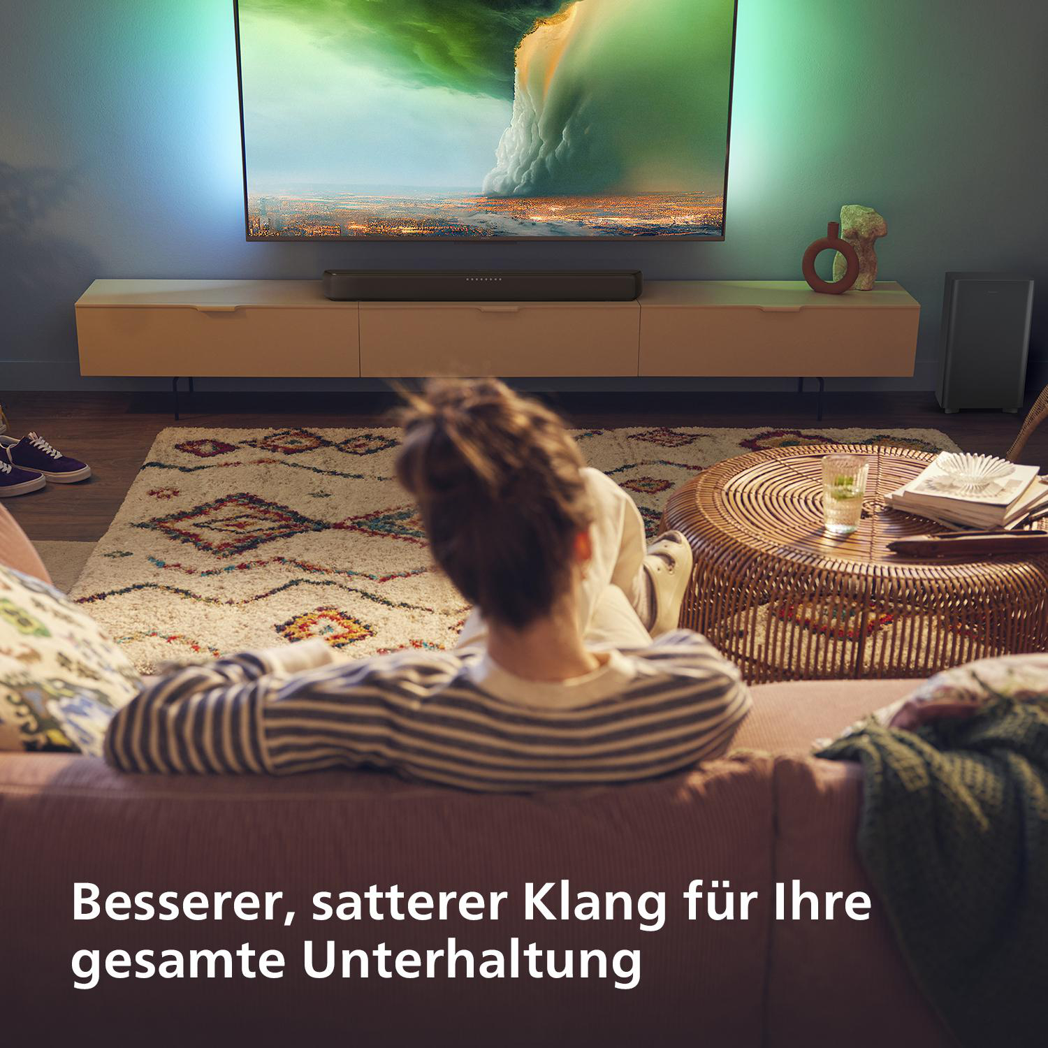 Person schaut fern. TV über Schrank. Sofa und Teppich im Vordergrund.