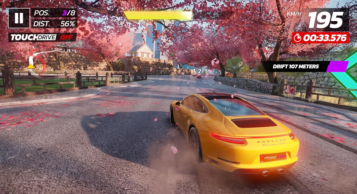 Un Porsche amarillo derrapa en una pista en un juego con flores de cerezo y paisaje urbano.