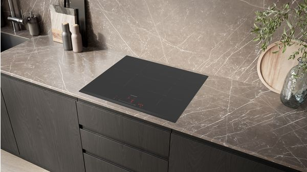Una placa de cocina negra empotrada sobre una encimera de mármol con un gabinete de madera oscura.