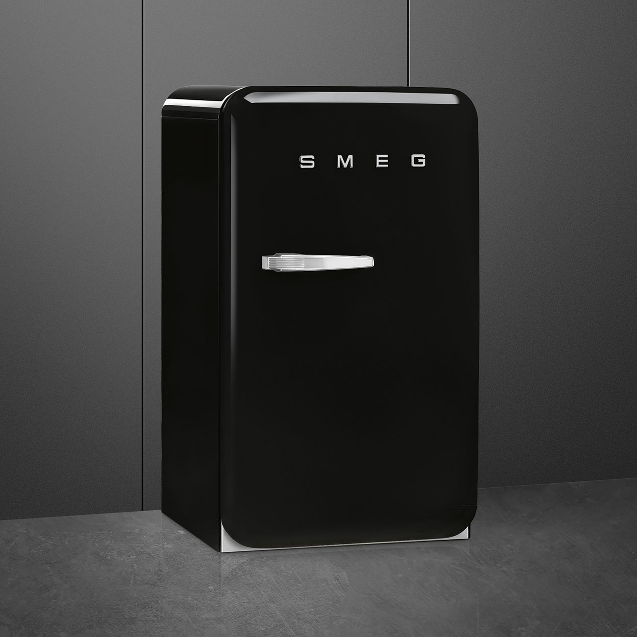 Schwarzer SMEG-Kühlschrank. Er hat einen Griff und steht auf einer grauen Oberfläche.