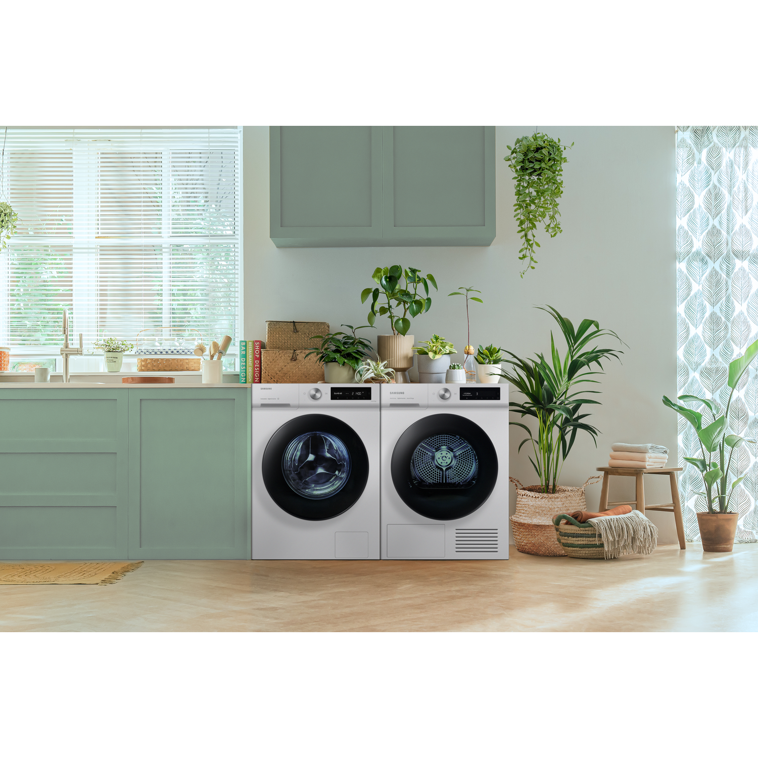 White washing machine and dryer set in a laundry room with plants.