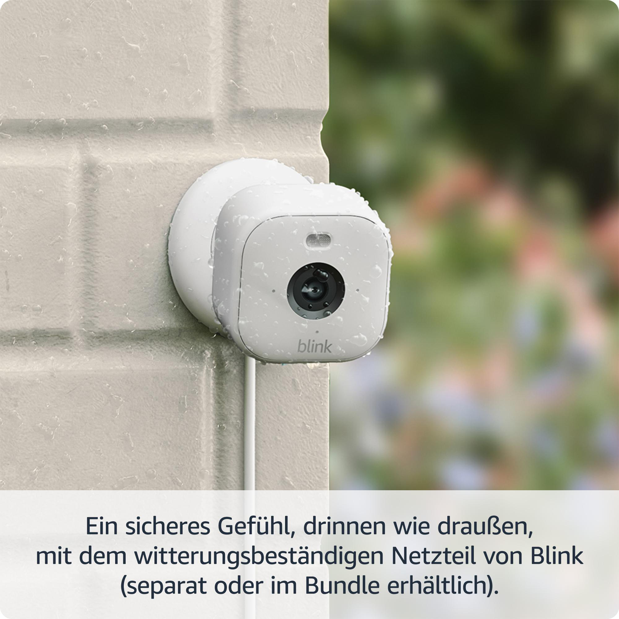 Eine weiße Blink-Sicherheitskamera ist an einer Backsteinmauer befestigt, nass.