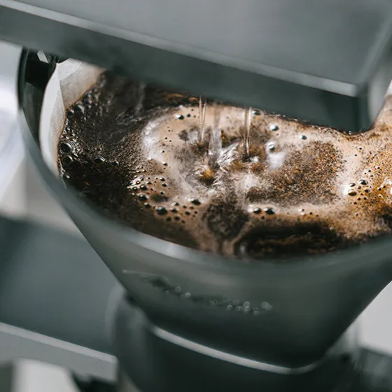 Versare acqua in un filtro per caffè con fondi di caffè. L'immagine è in primo piano.