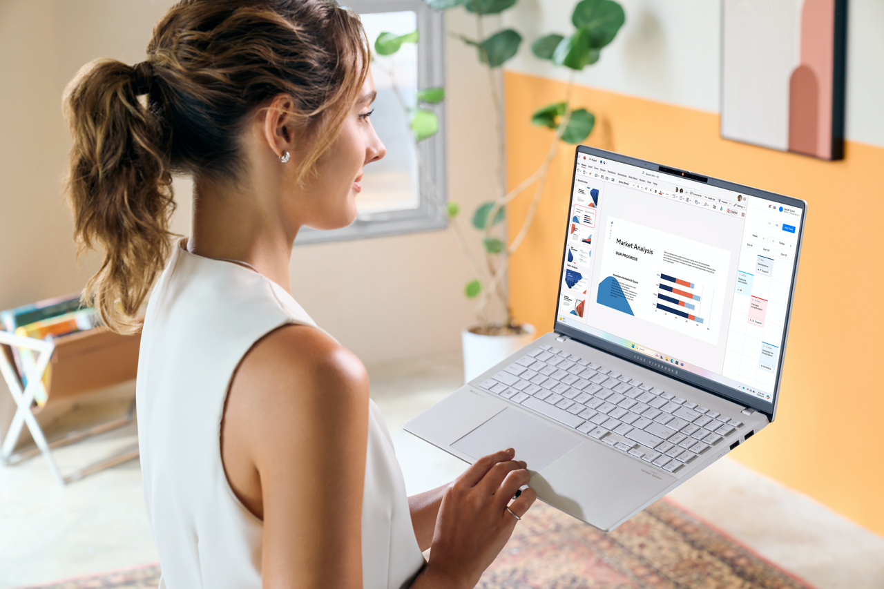 Eine Frau hält einen weißen Laptop und schaut auf den Bildschirm.