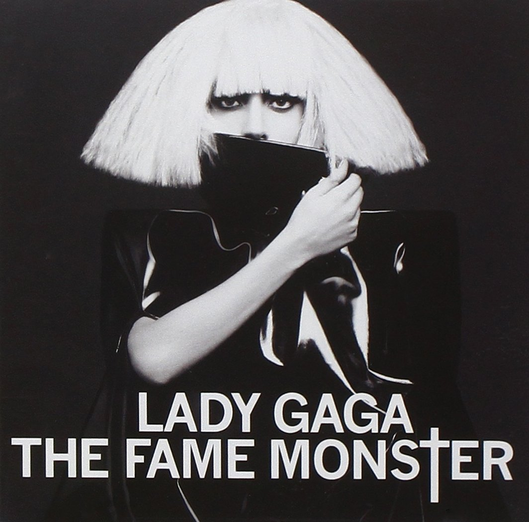 Lady Gaga, fekete ruhában és szőke parókában, kezével takarja a száját.