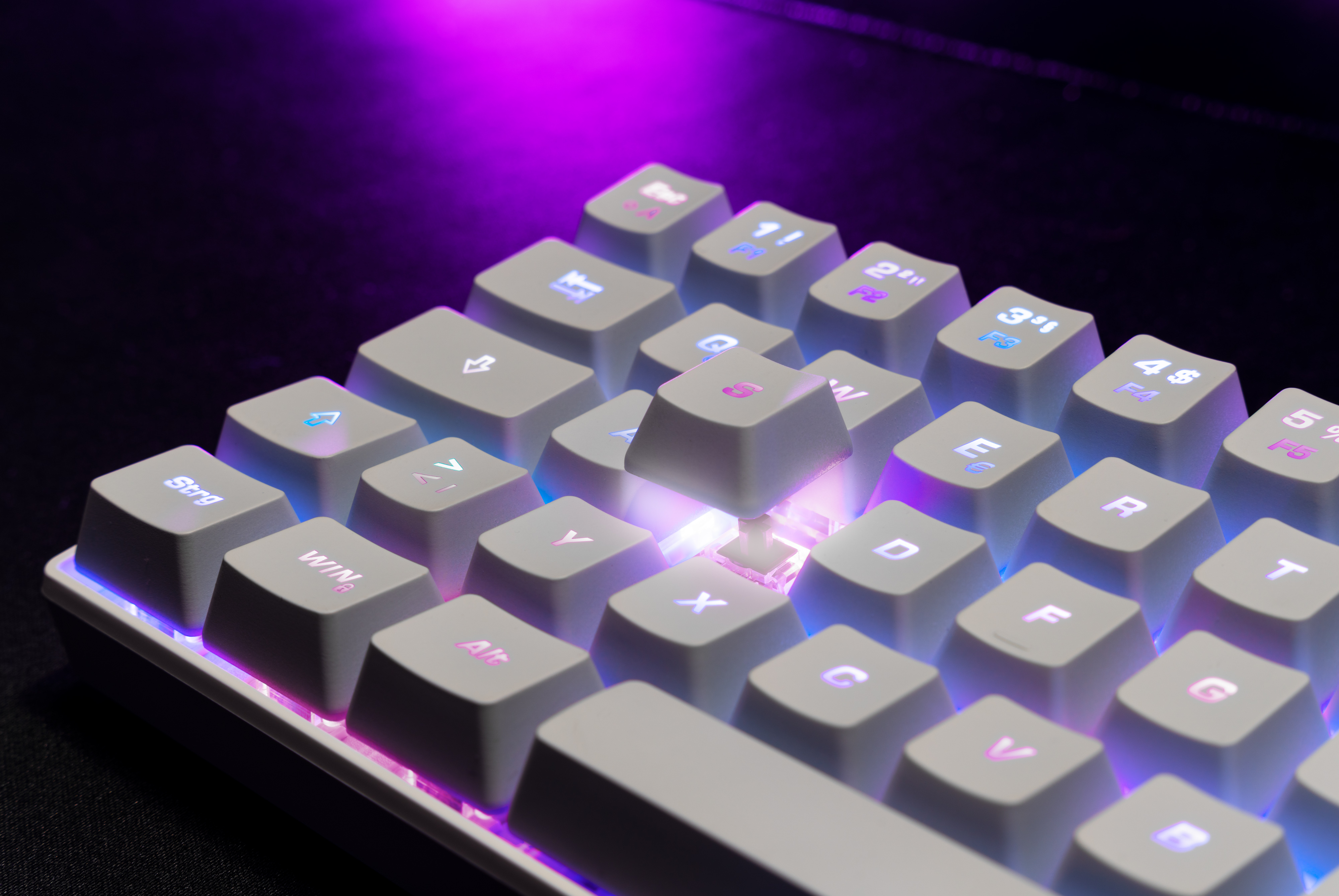 Zbliżenie podświetlanej białej klawiatury z podświetlanymi klawiszami.