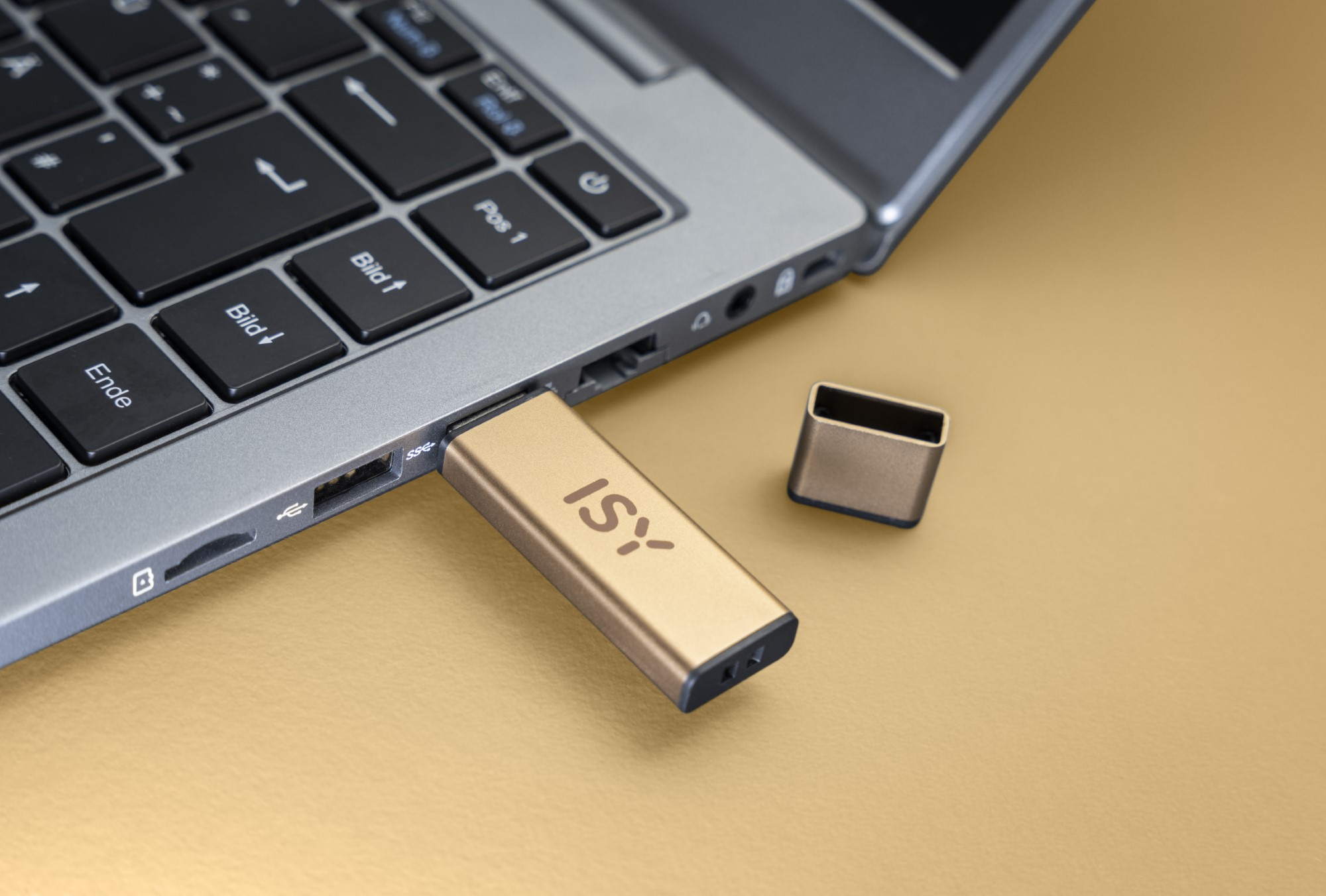 Złoty pendrive wpięty do laptopa, z nasadką obok.