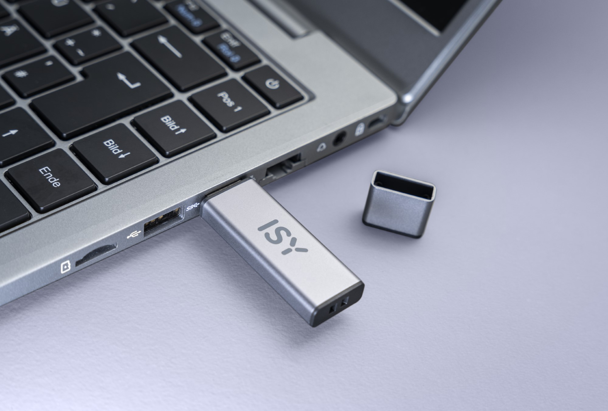 Srebrny pendrive podłączony do laptopa. Marka ISY jest widoczna.